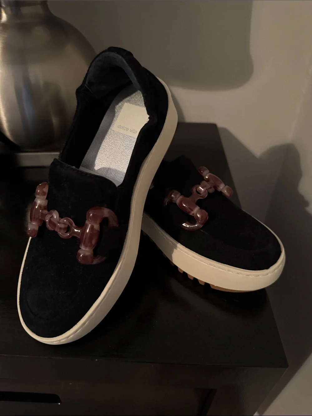 Dolce Vita Black Suede women’s Slip-On Loafers with Brown Accent Chain.